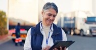 Fleet manager using a tablet near commercial trucks while reviewing truck tire maintenance and fleet management information.