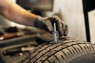 Technician measuring tire tread depth during a tire wear inspection.