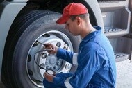 Technician checking tire pressure on a semi truck tire.