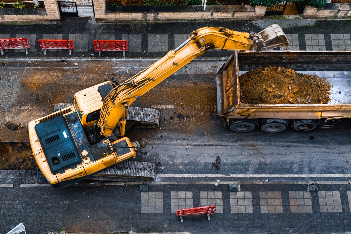 Excavator loading a dump truck at an urban construction site