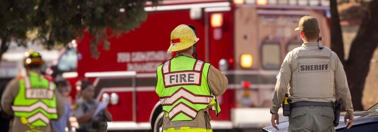 Firefighters and sheriff's officer at an emergency scene with a fire truck