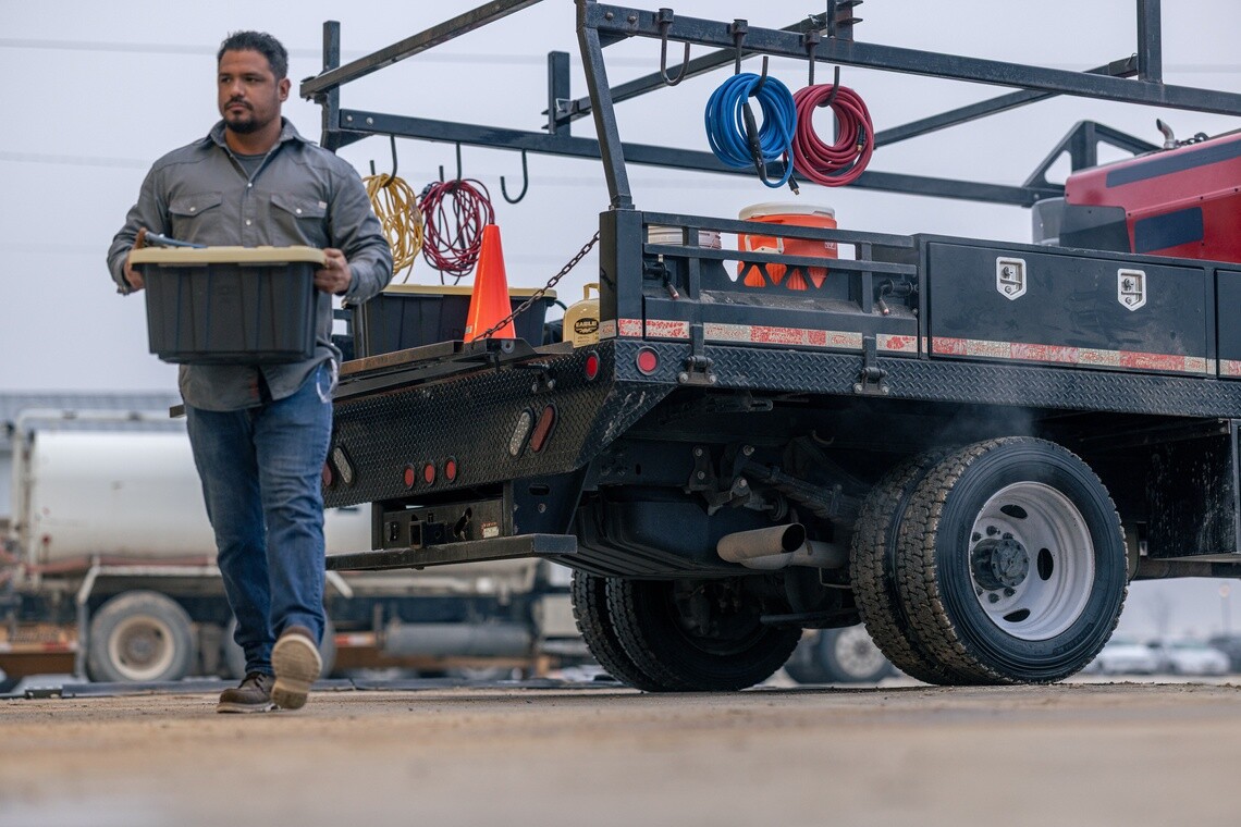 Worker carrying equipment beside a commercial work truck equipped with Michelin Agilis tires