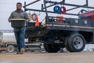 Worker carrying equipment beside a commercial work truck equipped with Michelin Agilis tires