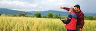 Two people using a laptop in an agricultural field