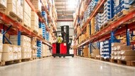 Forklift operator moving materials between warehouse storage racks