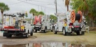 Utility trucks with cable reels parked outdoors