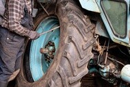 Person working on the wheel of a tractor with a large agricultural tire