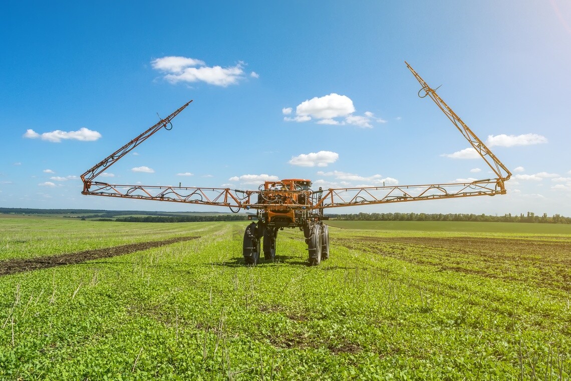 Self-propelled agricultural sprayer with extended booms in a field.