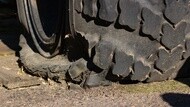 Close-up of a heavily damaged off-road tire with torn tread and sidewall rubber.