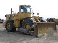 Yellow Caterpillar wheel dozer with large rubber tires and a front-mounted blade