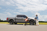 woman leaning on SUV with Michelin Defender LTX M/S2 tires looking at daughter running