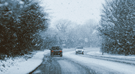 Two cars driving past each other on the road through the snow.